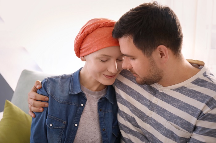 Fotografía en la que una mujer con cáncer apoyándose en su pareja.