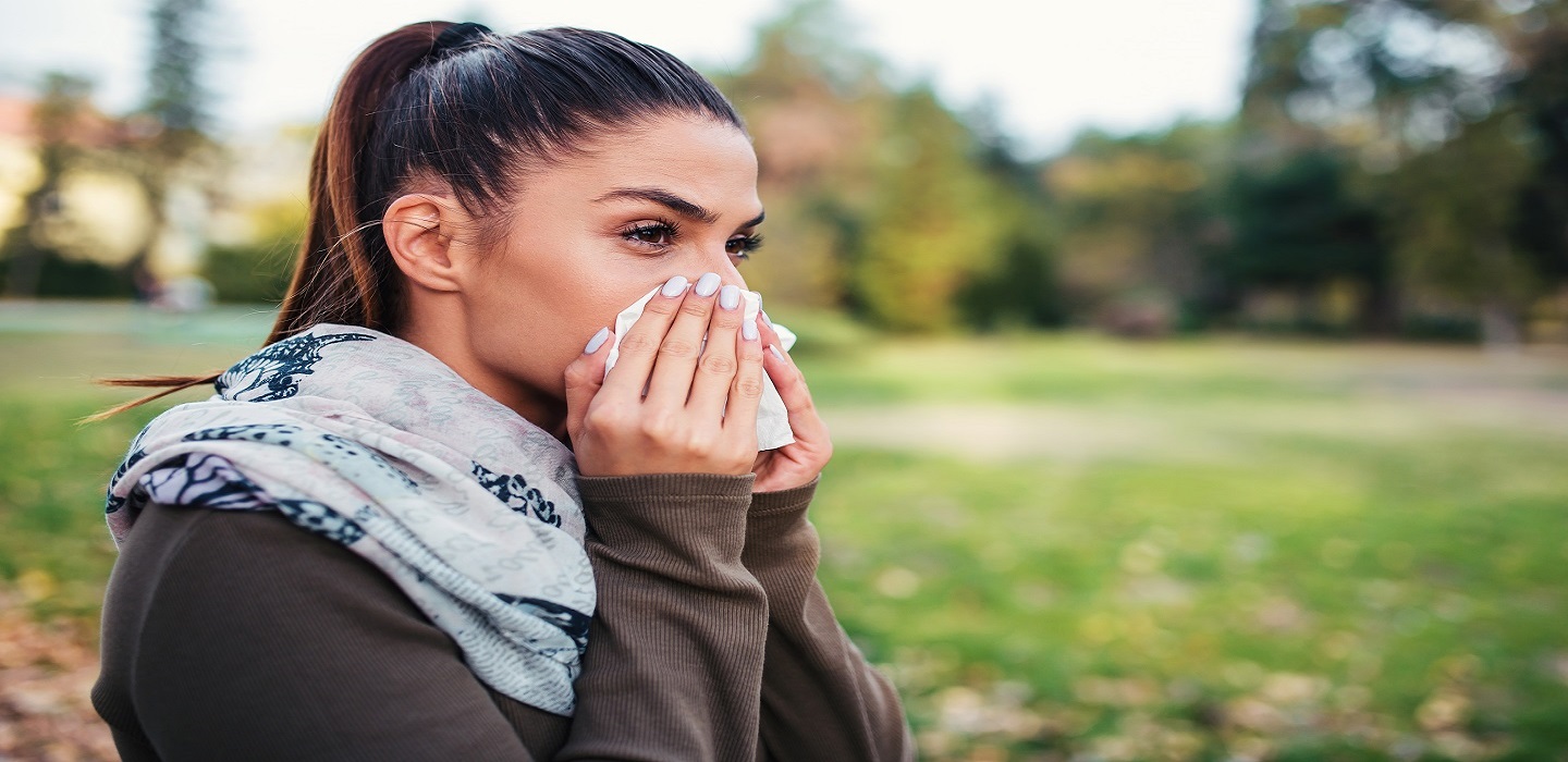 Mujer estornudando en el campo en la época de alergia primaveral.