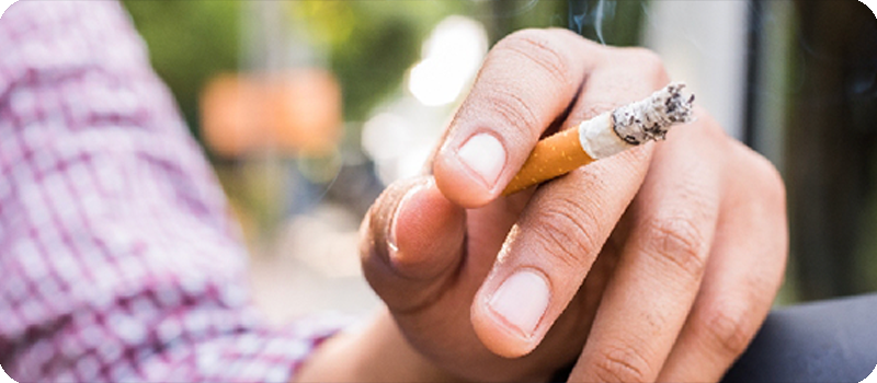 Mano sujetando el cigarro encendido